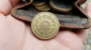 Moneta da 10 centesimi del Portogallo 2002 in primo piano su un portamonete di pelle con altre monete