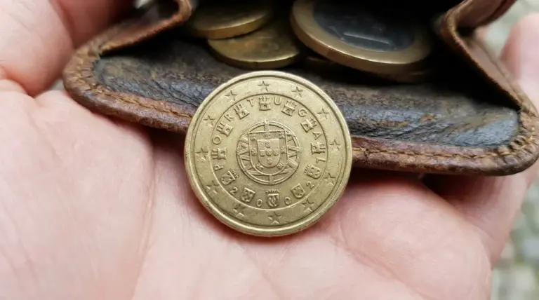 Moneta da 10 centesimi del Portogallo 2002 in primo piano su un portamonete di pelle con altre monete