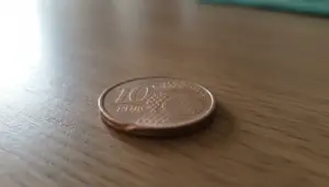 Moneta da 10 centesimi euro appoggiata su un tavolo di legno, vista in primo piano