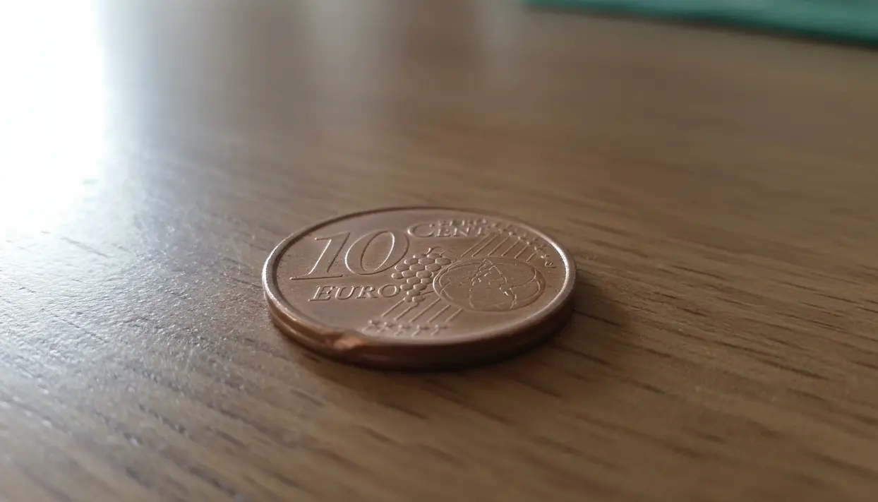 Moneta da 10 centesimi euro appoggiata su un tavolo di legno, vista in primo piano