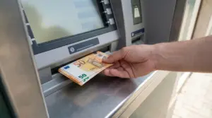 Una mano preleva banconote da 50 euro da uno sportello bancomat