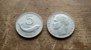 Due vecchie monete italiane da 5 lire, una con un delfino e l'altra con un profilo femminile