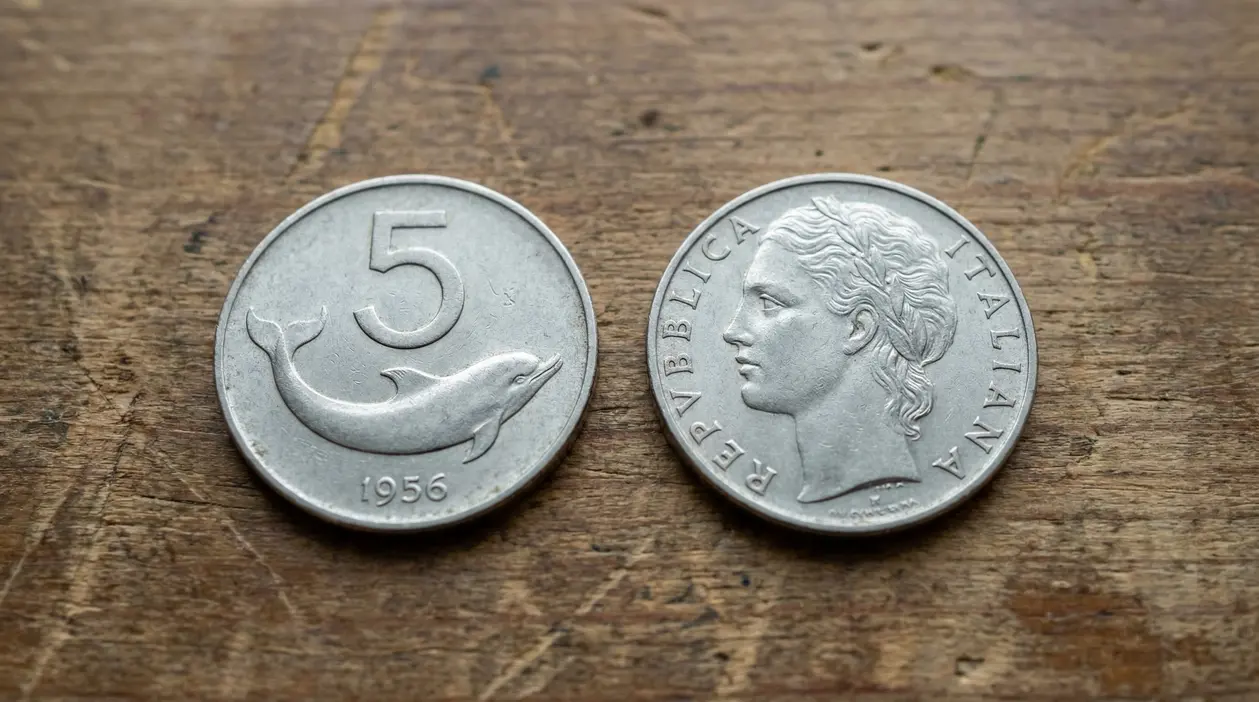 Due vecchie monete italiane da 5 lire, una con un delfino e l'altra con un profilo femminile