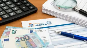 Modulistica fiscale con banconote in euro, calcolatrice, penna e lente d’ingrandimento su una scrivania