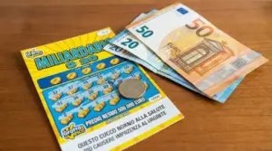 Biglietto gratta e vinci con una moneta da un euro e banconote su un tavolo di legno