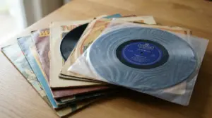 Pila di dischi in vinile con copertine vintage su un tavolo, con un LP in primo piano nella busta interna